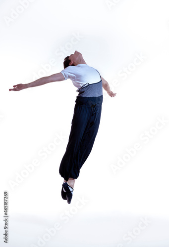 Concepts of Dancing. Professional Caucasian Male Ballet Dance Performing in Flight With Hands Outspread in Studio Against White Background.