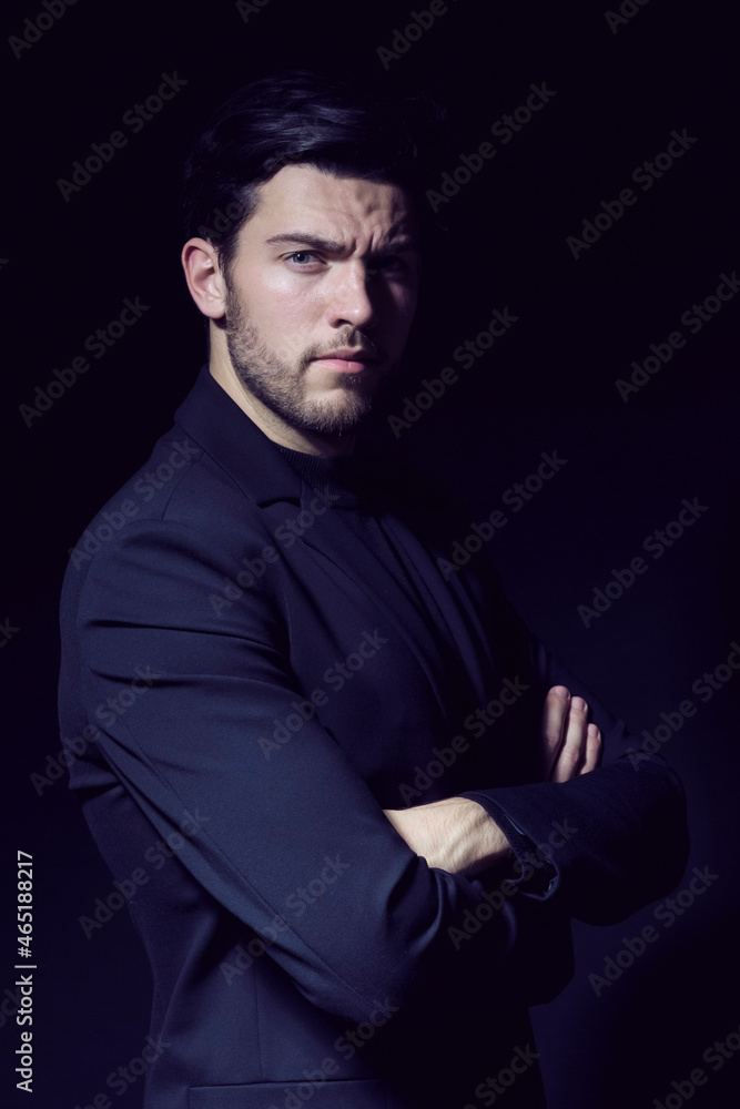 Portrait of Handsome Caucasian Brunet Businessman Wearing Black Suit Posing With Hands folded Against Black