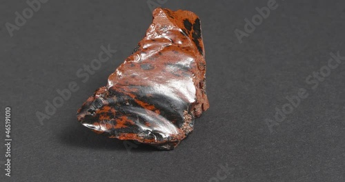 Obsidian mahogany. Igneous rock. Rotation on a dark background. photo