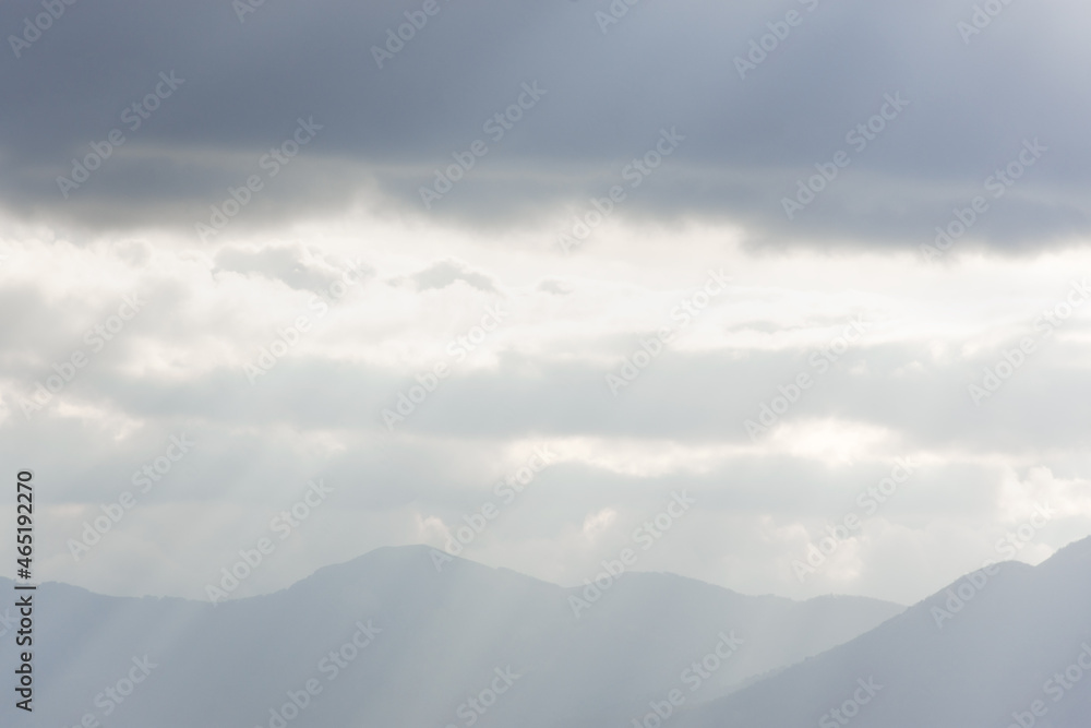 Blue mountains clouds rays. Bright sunlight through the fog illuminates the peaks. Atmospheric natural background copy space. Calm neutral gray autumn landscape. The concept of freedom, relaxation