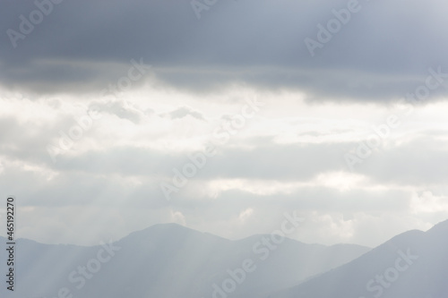 Blue mountains clouds rays. Bright sunlight through the fog illuminates the peaks. Atmospheric natural background copy space. Calm neutral gray autumn landscape. The concept of freedom, relaxation © Anna Pismenskova