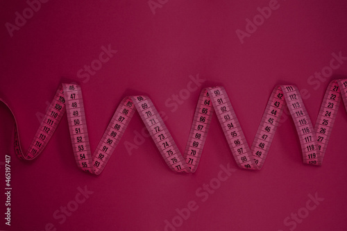 Measure tape on the pastel pink background. Mock up for body slimming, weight loss or dressmaker's offer or other ideas. Empty place for text, logo or object