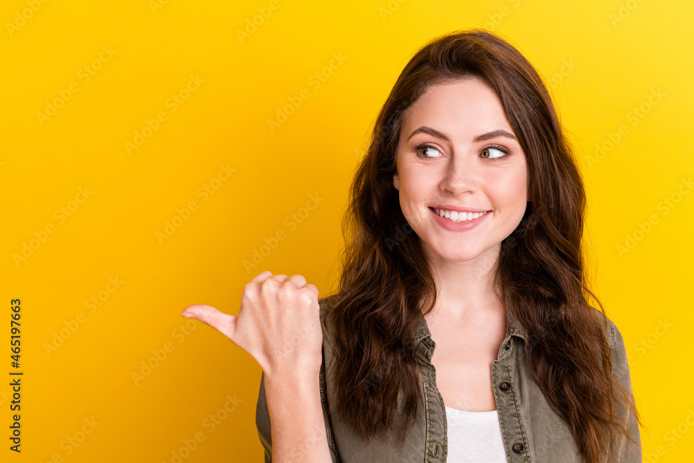 Portrait of charming cheerful person look indicate thumb empty space proposition isolated on yellow color background Portrait of charming cheerful person look indicate thumb empty space proposition isolated on yellow color background