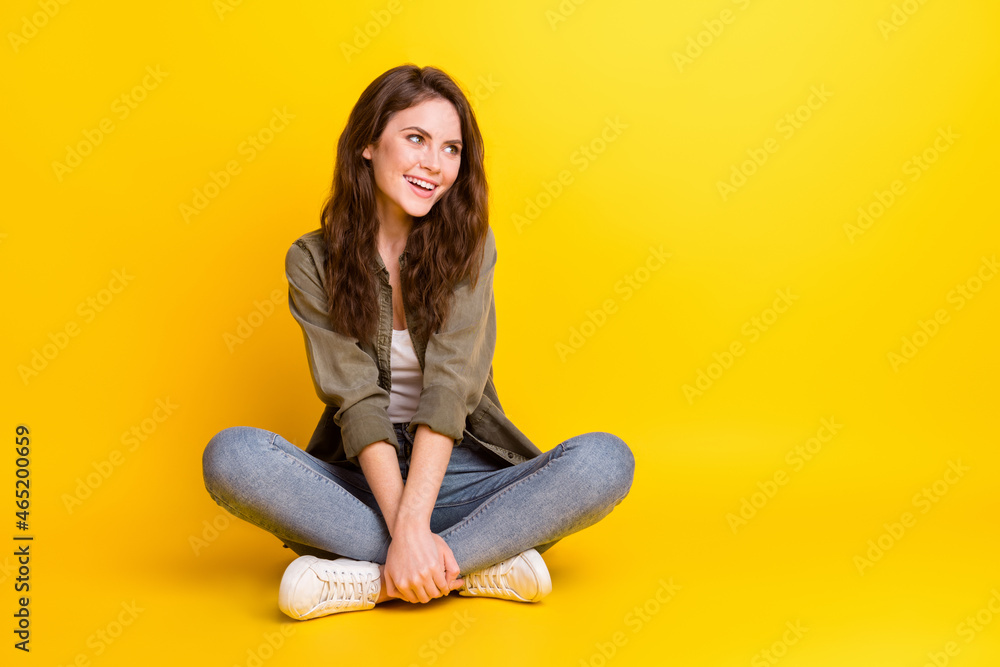 Portrait of attractive cheerful girl sitting in lotus pose fantasizing copy space isolated over bright yellow color background Portrait of attractive cheerful girl sitting in lotus pose fantasizing copy space isolated over bright yellow color background