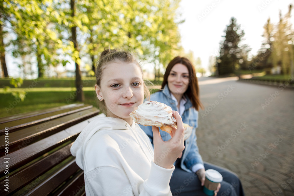 Girl having sweet food while sitting with mother on bench Girl having sweet food while sitting with mother on bench
