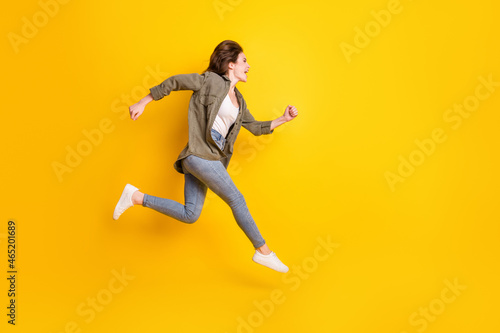 Full length body size view of attractive cheerful glad girl jumping running marathon isolated over bright yellow color background