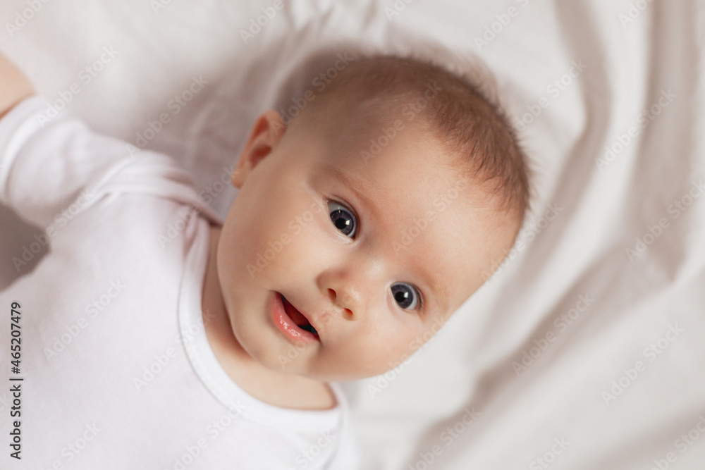 portrait of a cute smiling newborn baby in a white bodysuit on a white background close up. products for children. concept of happy childhood and motherhood. child care. High quality photo portrait of a cute smiling newborn baby in a white bodysuit on a white background close up. products for children. concept of happy childhood and motherhood. child care. High quality photo