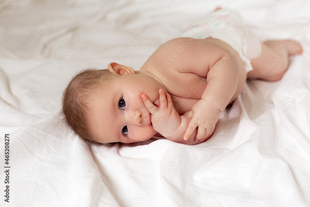 cute thoughtful newborn baby is lying on its side on a white bed. products for children. concept of a happy childhood and motherhood. child care. space for text. High quality photo cute thoughtful newborn baby is lying on its side on a white bed. products for children. concept of a happy childhood and motherhood. child care. space for text. High quality photo