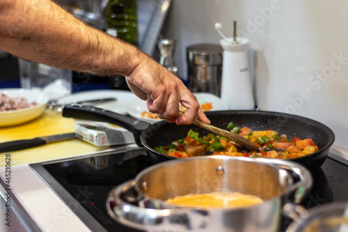 One unrecognizable man cooking and stirring vegetables in a frying pan. close up. Selective focus.