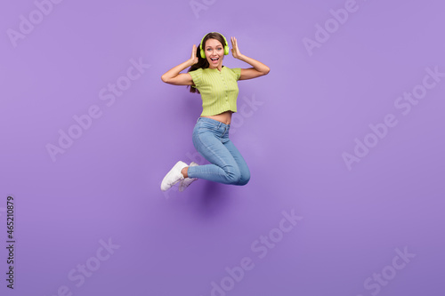 Full length body size view of pretty cheerful girl jumping listening rock having fun isolated over purple violet color background