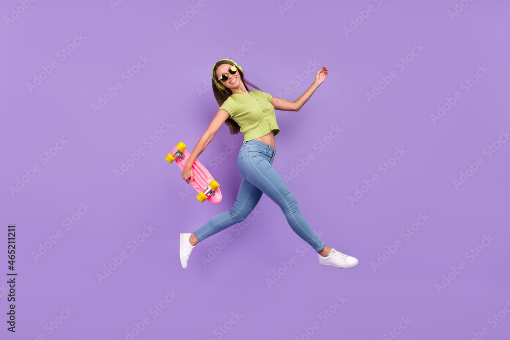 Full length body size view of nice trendy cheerful girl jumping listening song having fun going isolated over purple violet color background Full length body size view of nice trendy cheerful girl jumping listening song having fun going isolated over purple violet color background