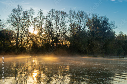 An old landing stage in a lake on a early morning in Autumn with bits of mist in the Dutch town Valkenburg surrounded by beautiful colors and reflections during sunrise