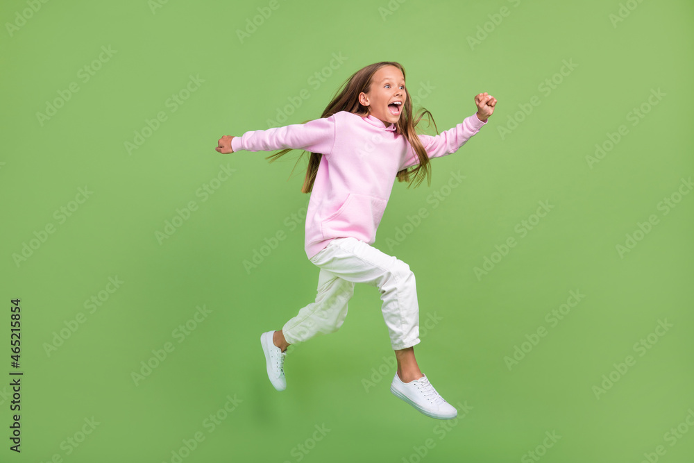 Full length photo of impressed small blond girl run wear sweatshirt trousers sneakers isolated on green background Full length photo of impressed small blond girl run wear sweatshirt trousers sneakers isolated on green background