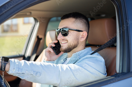 Young man speaking by phone while driving his car.
