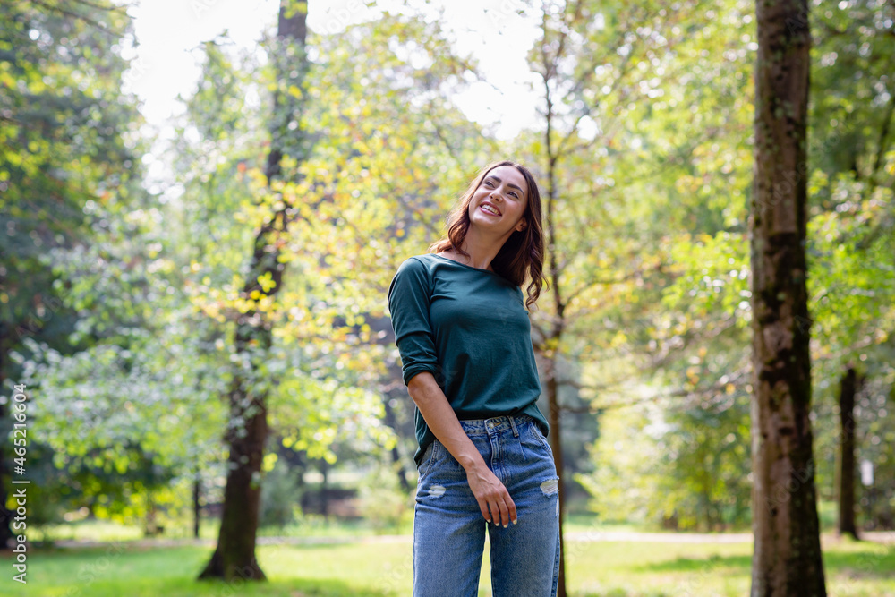 Thoughtful young woman smiling while standing at park Thoughtful young woman smiling while standing at park