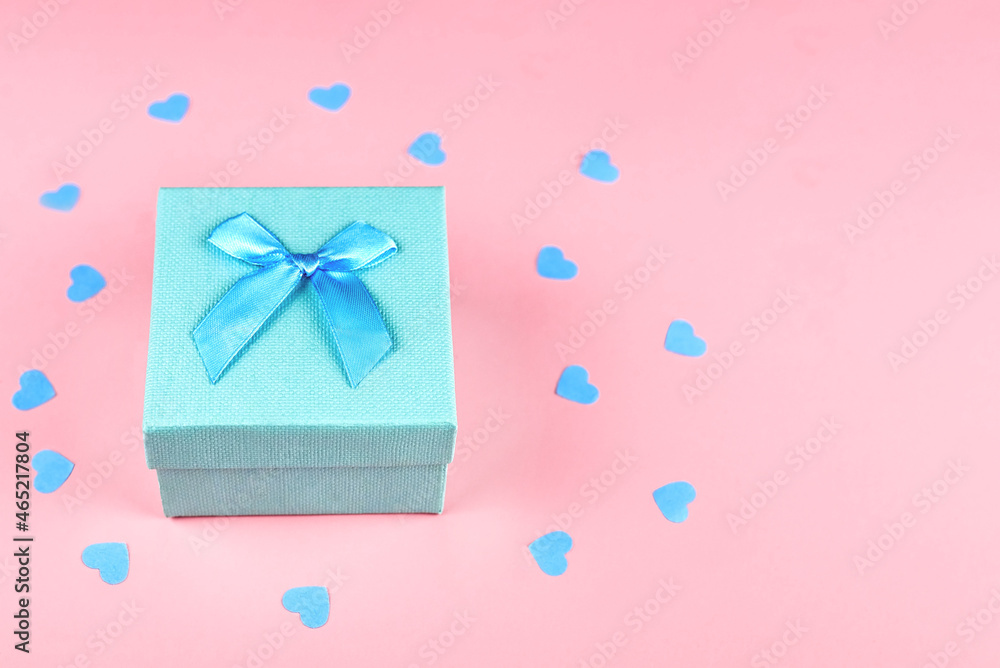 Gift box with a bow on a pink background with hearts confetti. Gift box with a bow on a pink background with hearts confetti.
