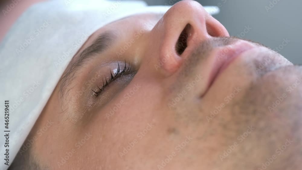 Closeup of man's lashes after lash laminating lifting procedure in beauty salon. Closed eye with black long curly eyelashes after professiona lash lamination in cosmetology clinic, face closeup. Closeup of man's lashes after lash laminating lifting procedure in beauty salon. Closed eye with black long curly eyelashes after professiona lash lamination in cosmetology clinic, face closeup.