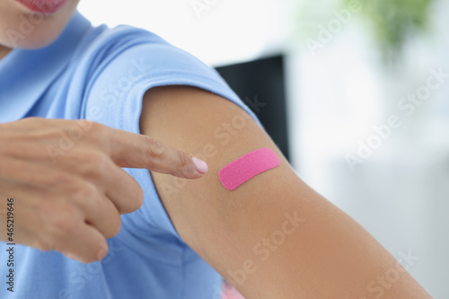 Woman showing her index finger to patch at injection site of flu vaccine closeup