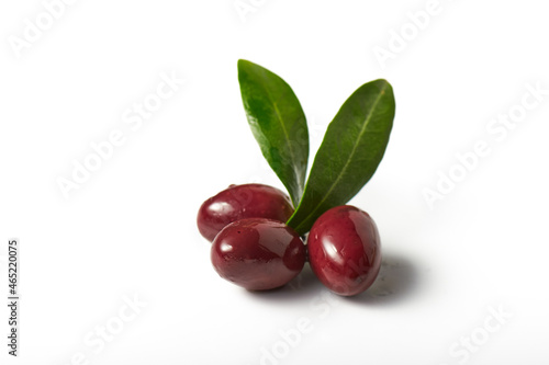 Kalamata olives with leaves soaked in olive oil over white background.