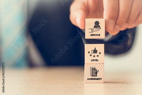 SLA - Service Level Agreement acronym, business concept. Service performance tracking to reduce the uncertainty the customer in process. Hand holds  wooden cubes with Service Level Agreement symbols. photo