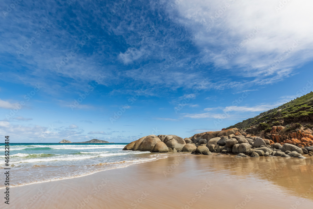 Sky over sandy coastal beach in summer with boulders in background, Australia Sky over sandy coastal beach in summer with boulders in background, Australia