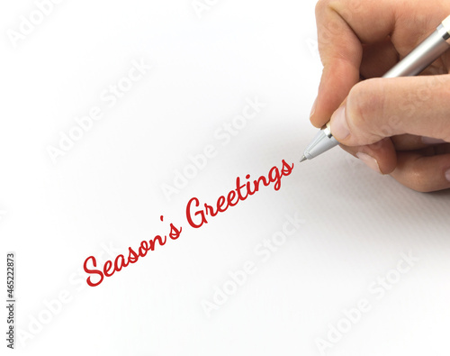 Hand writing "Season's Greetings" on white sheet of paper.