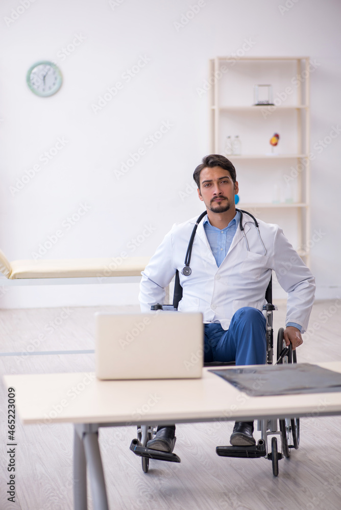 Young male doctor in wheel-chair working in the clinic