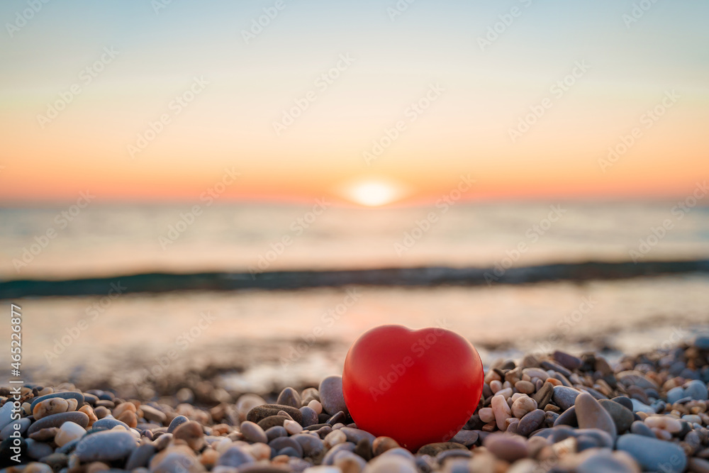 Beautiful pebbles and a red heart on a quiet calm beach at sunset. The concept of serenity and relaxation. Summer vacation at the sea Beautiful pebbles and a red heart on a quiet calm beach at sunset. The concept of serenity and relaxation. Summer vacation at the sea