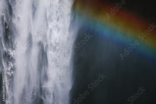 Powerful waterfall and rainbow in rocky gorge