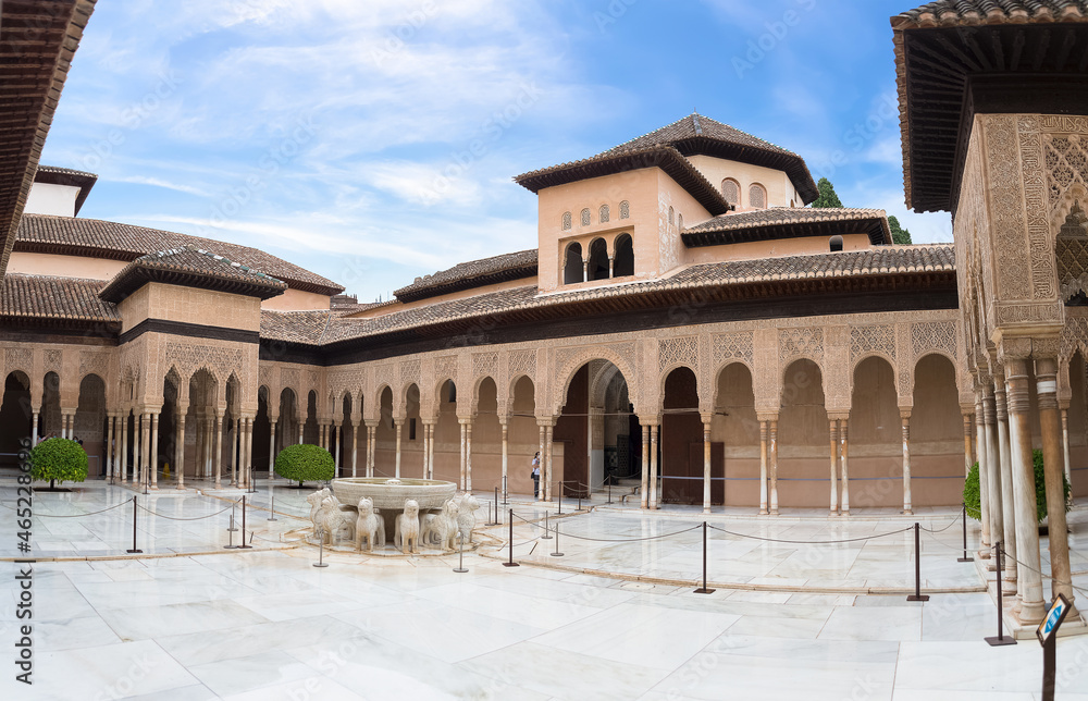 Full panoramic exterior view at the Patio at the Lions, twelve marble lions fountain on Palace of the Lions or Harem, Alhambra citadel, tourist people visiting