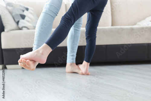 Bare feet mom and daughter dancing on floor of house closeup