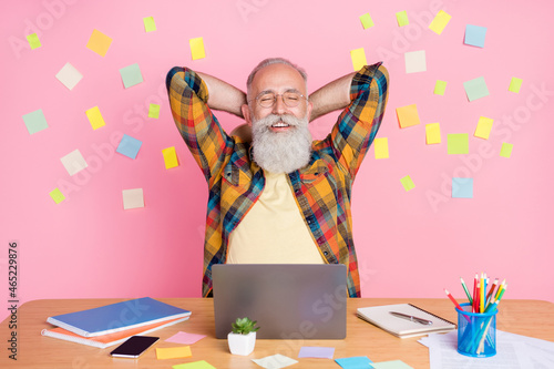 Photo of relaxing cute mature man dressed checkered shirt sitting desk arms behind head smiling isolated pink stickers color background