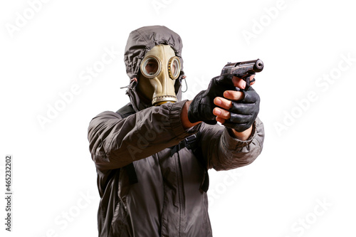 An isolated shot of a man dressed in a gas mask, a hooded jacket, a backpack, gloves, holding a gun in his hands and aiming to the right. On a white isolated background