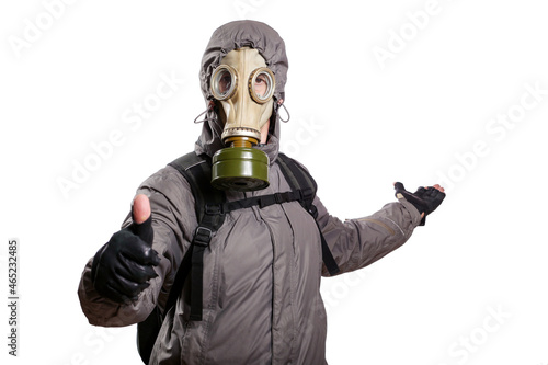 An isolated shot of a man dressed in a gas mask, a hooded jacket, a backpack, shows a gesture of okey, the other hand stretched back indicating the direction, looking into the camera. On a white