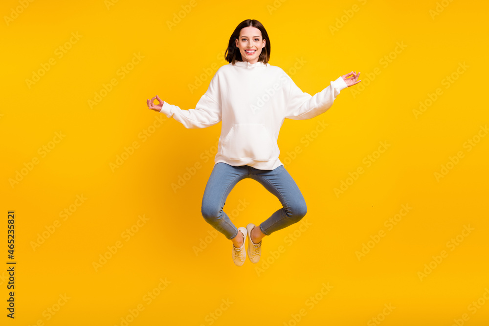 Photo of sporty lady jump yoga practice wear white hoodie jeans sneakers isolated yellow color background Photo of sporty lady jump yoga practice wear white hoodie jeans sneakers isolated yellow color background