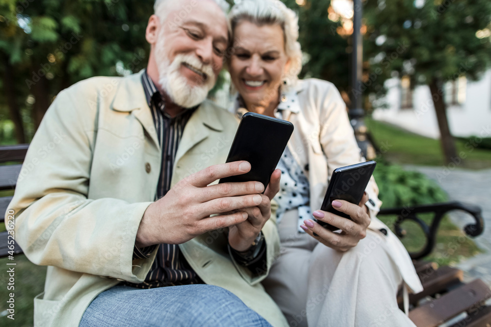 Couple using smart phone while sitting on bench Couple using smart phone while sitting on bench