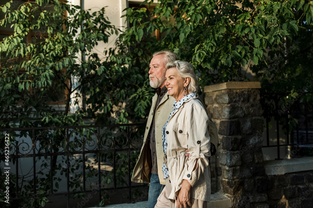 Smiling couple walking together by retaining wall Smiling couple walking together by retaining wall