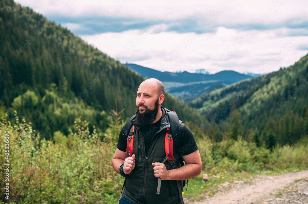 Man hiking in mountains with heavy backpack travel wandering lifestyle adventure concept summer vacation outdoors alone in the wild. Handsome bald bearded young man. Man hiking in mountains with heavy backpack travel wandering lifestyle adventure concept summer vacation outdoors alone in the wild. Handsome bald bearded young man.