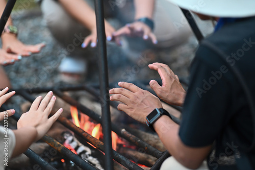 Closed up with a group of cheerful happy friends sitting at the bonfire for making warm. Outdoors activity, Hiking, Camping, Picnic concept.