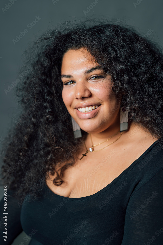 Voluptuous woman smiling against gray background Voluptuous woman smiling against gray background