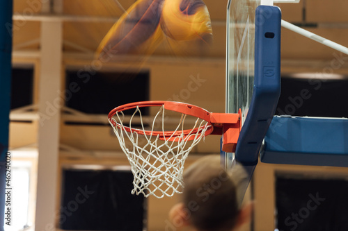 the ball flies into the basketball basket. the photo is on a long exposure. the goal of the team in a basketball match. winning a sports competition. blurred silhouette of the ball in motion
