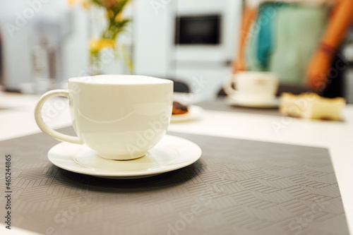 three empty white cups are on the kitchen table. pour fragrant morning coffee