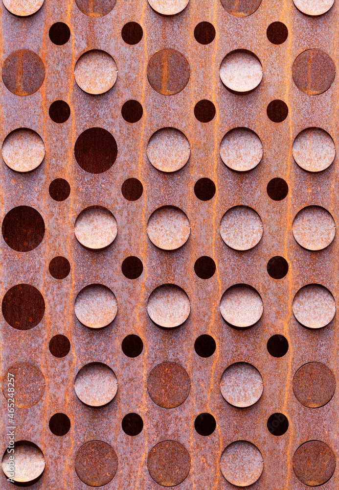 Rusty curly sheet of metal texture with round holes. Vertical image.