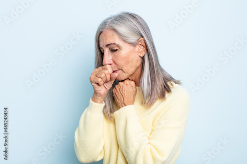 middle age gray hair woman feeling ill with a sore throat and flu symptoms, coughing with mouth covered