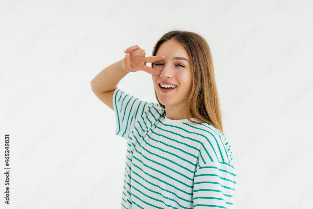 Happy beautiful young woman showing peace sign over grey background Happy beautiful young woman showing peace sign over grey background
