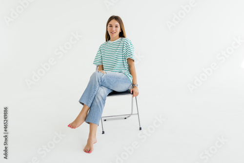 Beautiful young woman sitting on a chair and smiling, isolated over white background photo