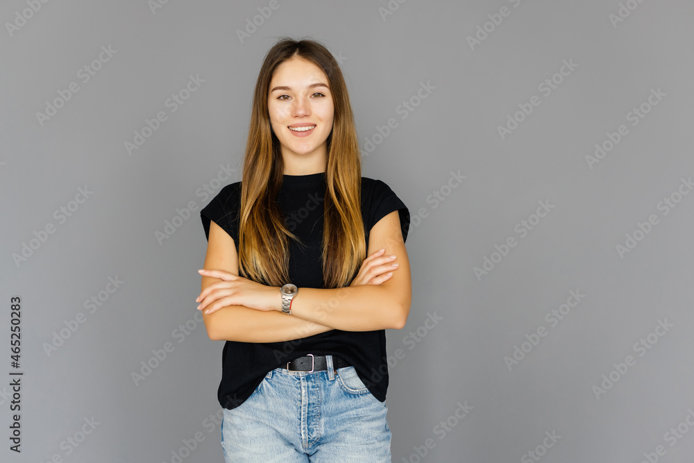 Portrait of a smiling woman in glasses and arms folded over gray background. Portrait of a smiling woman in glasses and arms folded over gray background.