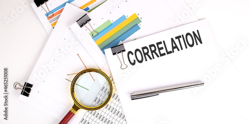 CORRELATION , text on white paper on the light background with charts paper photo