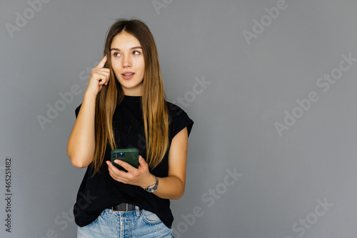 Portrait of remind woman looking at smartphone with troubled expression, reading message, waiting for call, studio, gray background, copy space
