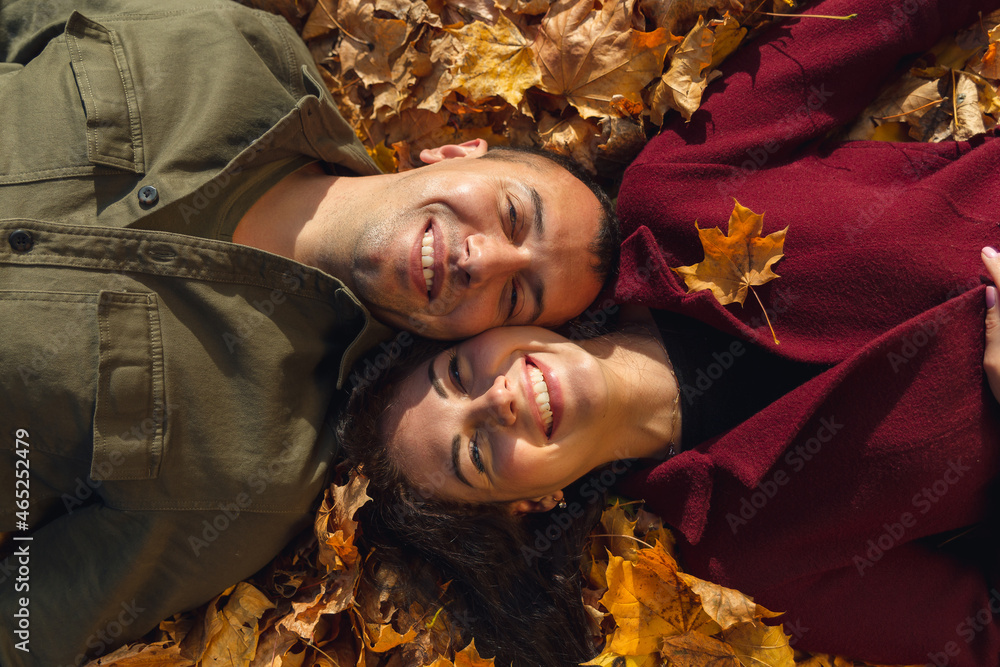 Top view of couple laying in autumn leaves.